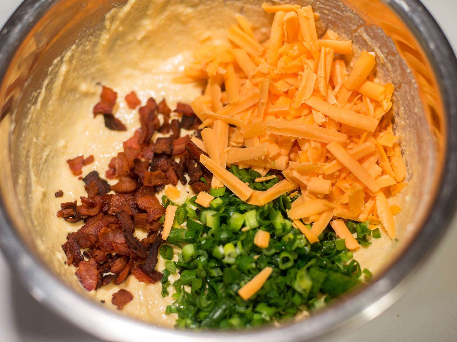 Bacon, cheddar, and scallion in a bowl with cornmeal batter.