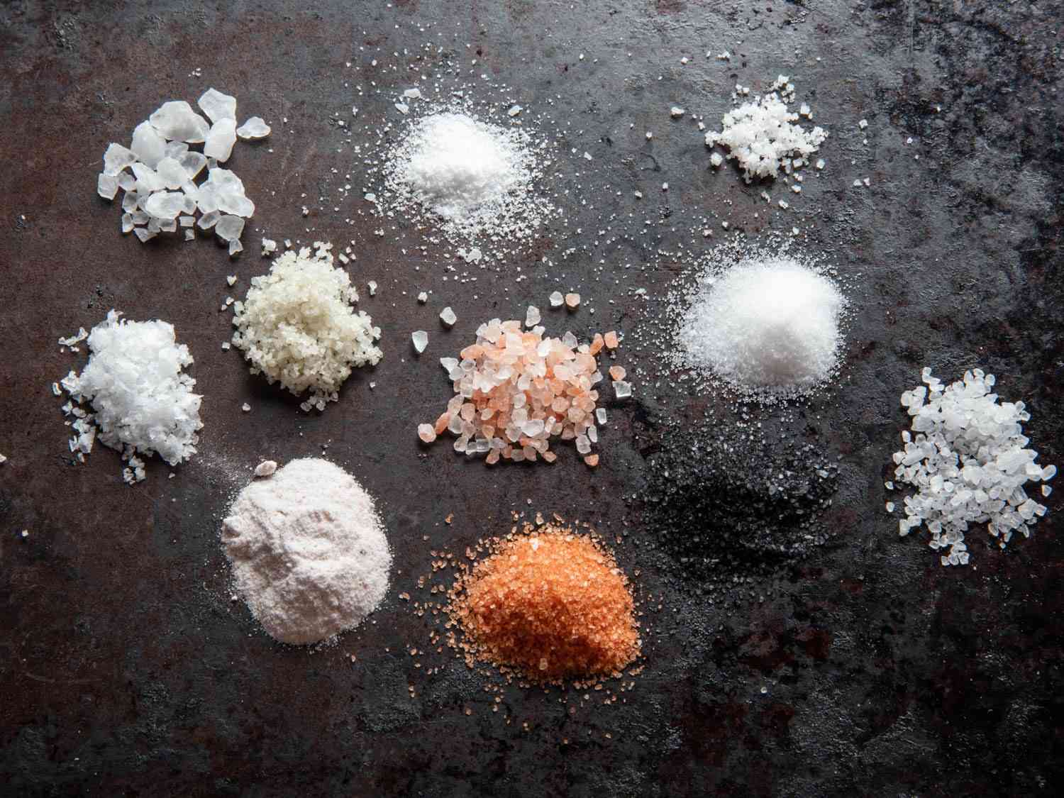 Piles of many different salt varieties to show the differences in color, texture, and size.