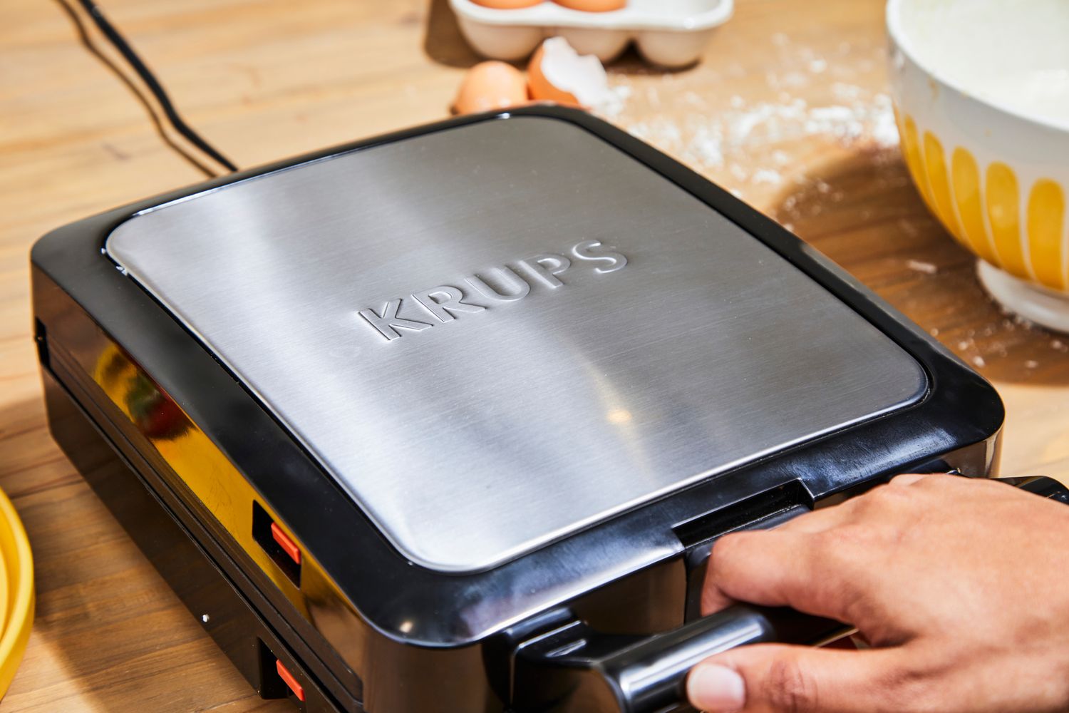 Person holding handle on Krups 4-Slice Belgian Waffle Maker