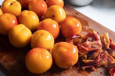 Peeled peaches on a cutting board.