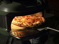 a person removing a pizza from the gozney tread