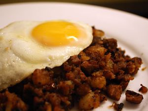 A plate of roast beef hash with a fried egg on top. 