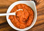 A small white bowl of ajvar, Serbian roasted red pepper sauce