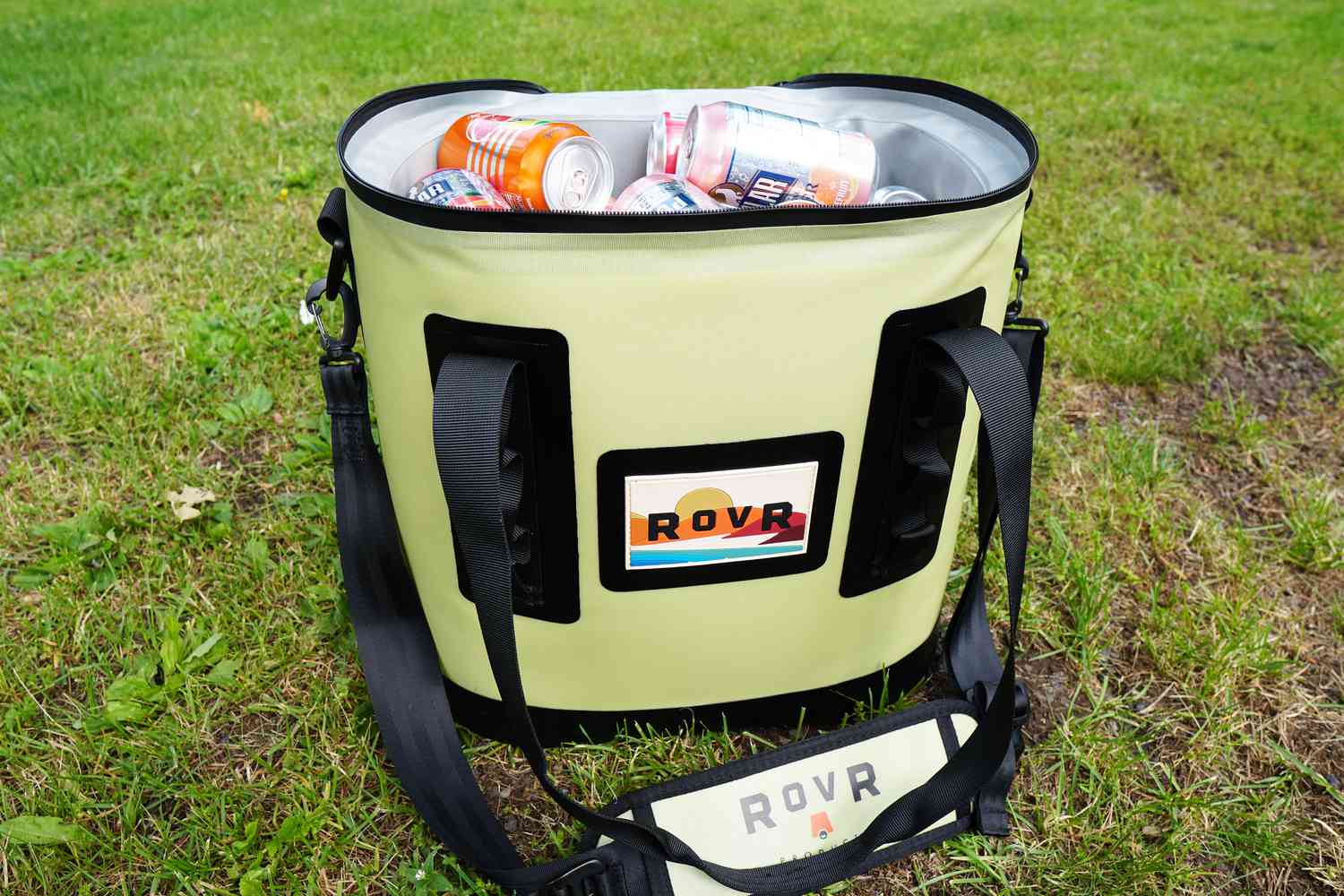 A green soft cooler with its lid open and filled with cans of seltzer