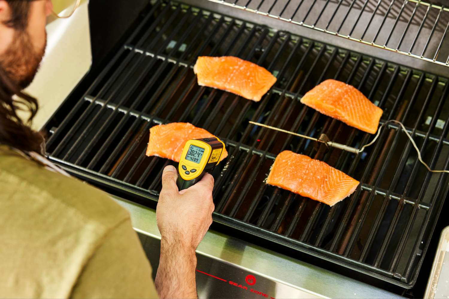 A person checks the temperature of salmon cooked in the Weber Genesis E-325 Liquid Propane Gas Grill