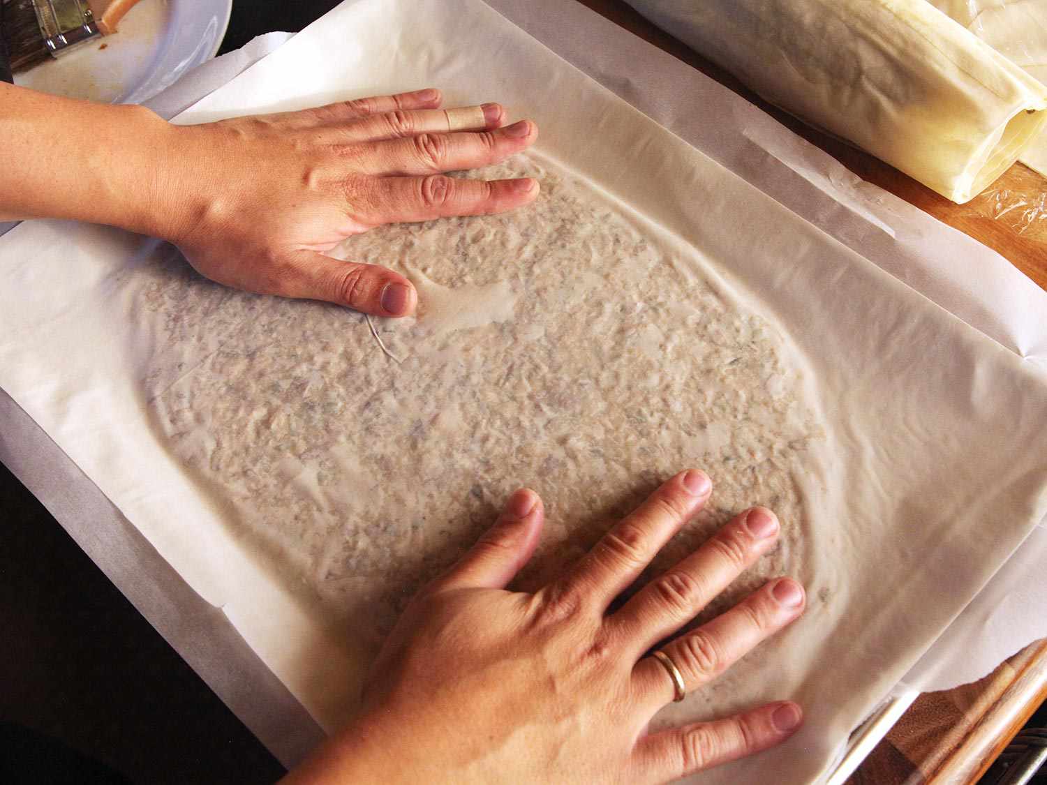 Pressing phyllo sheet onto flattened bean-cashew puree.