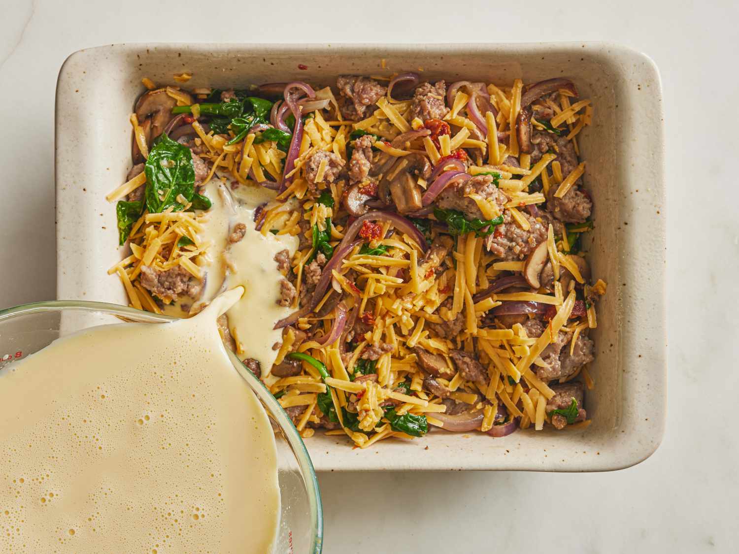 Filling casserole with egg mixture in a baking dish