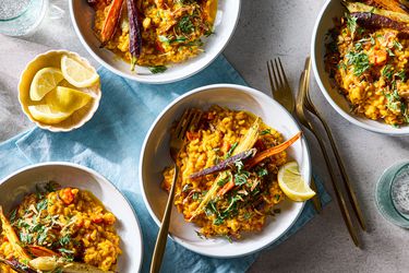 Plated carrot risotto with garnishes and lemon wedges