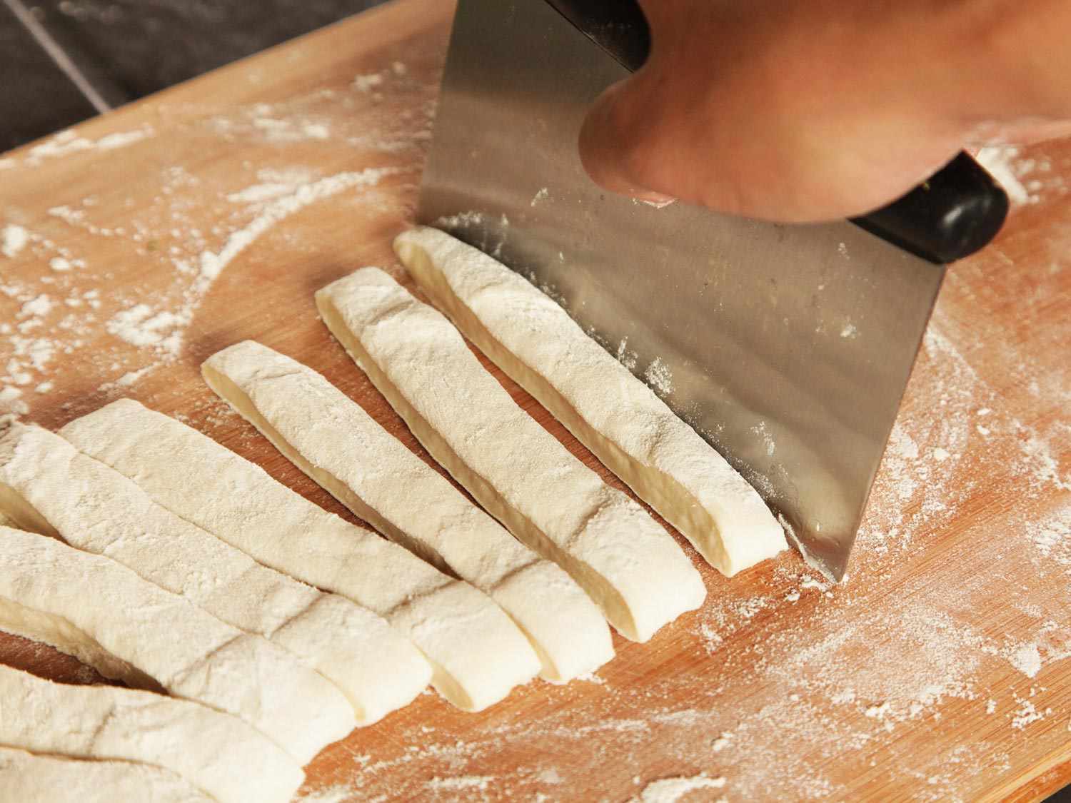 Slicing dough into strips for tying into knots for pepperoni garlic knots