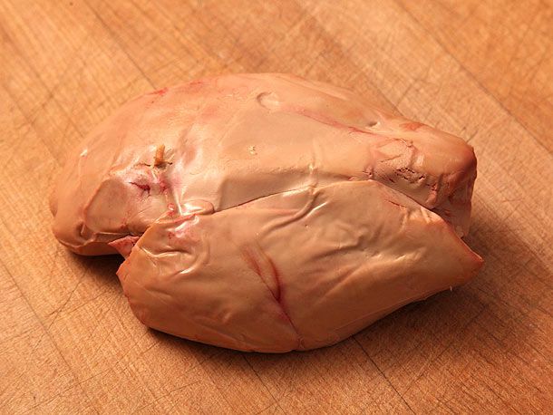 A whole lobe of foie gras resting on a cutting board.