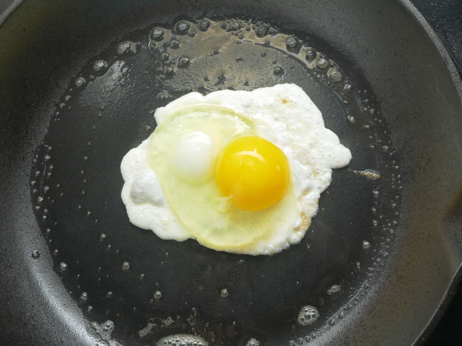 an egg in the center of a cast iron pan with a slightly rougher surface
