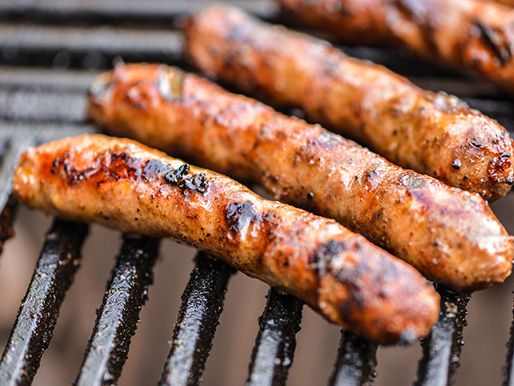 Browned Merguez sausages resting on a grill grate.