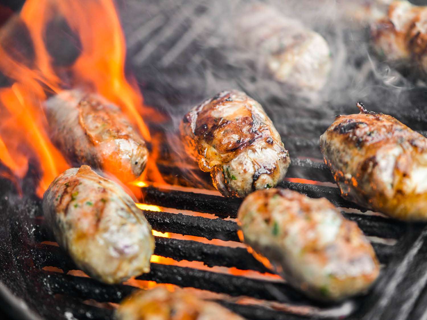 Flames threaten to engulf several sheftalia as their fat renders and creates flare-ups.