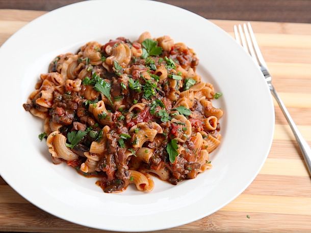 A plate of ridged crestos di gallos pasta that's been tossed with mushroom Bolognese sauce.