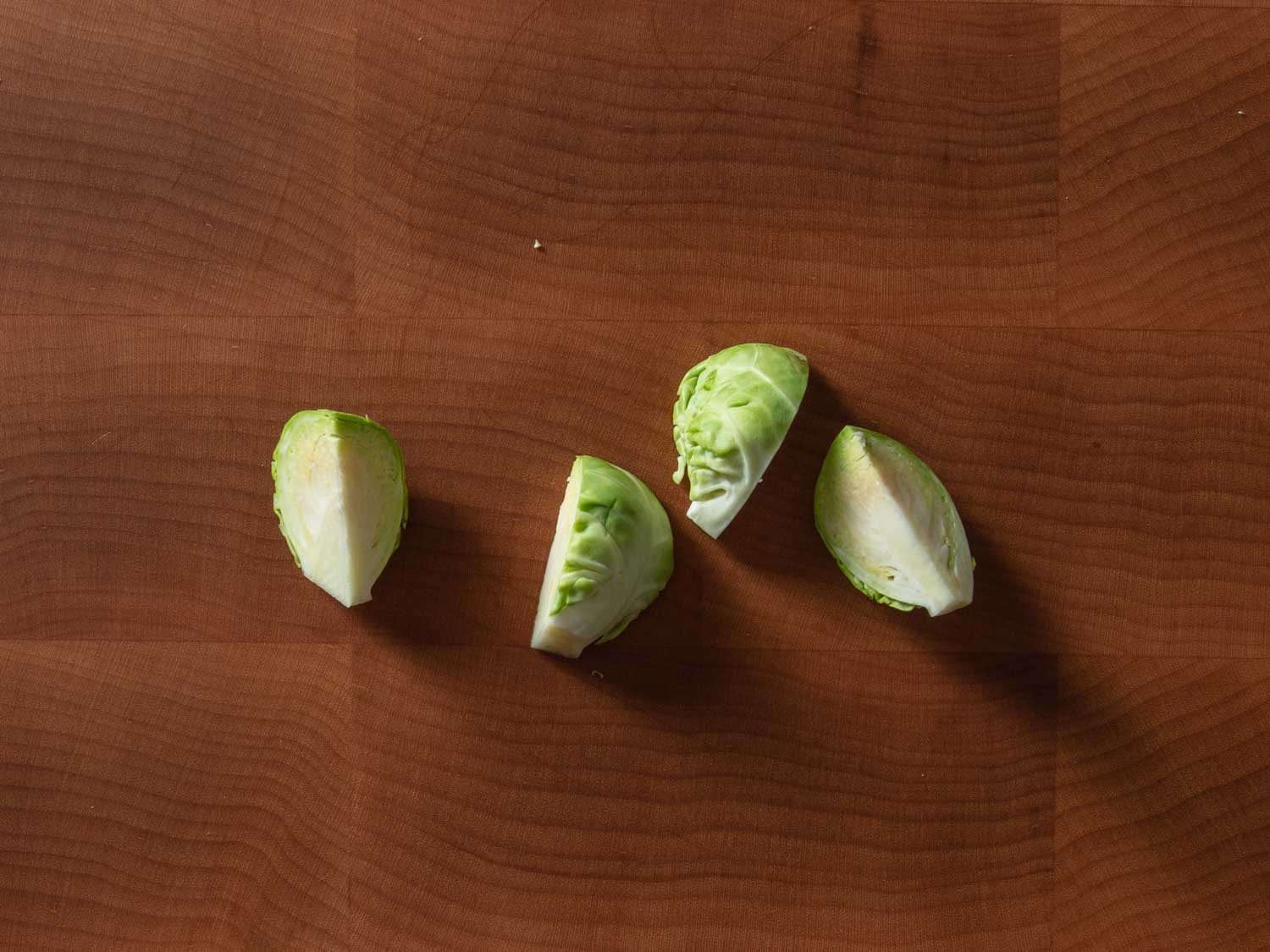 A Brussels sprout that has been cut into quarters lengthwise through the core.
