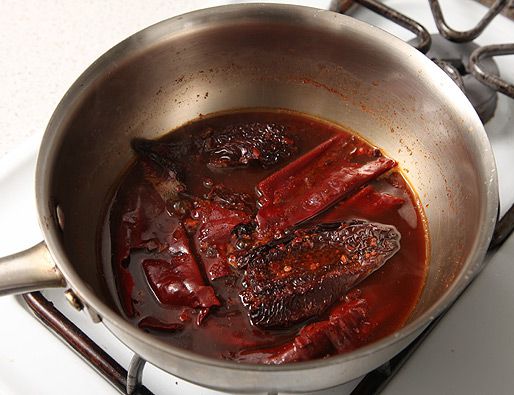 Dried chiles simmering in water in a pot. 