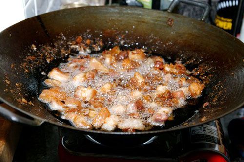 Pork belly cooking and browning in a wok.