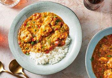 Shrimp étouffée in a soup plate with rice and thinly sliced scallions