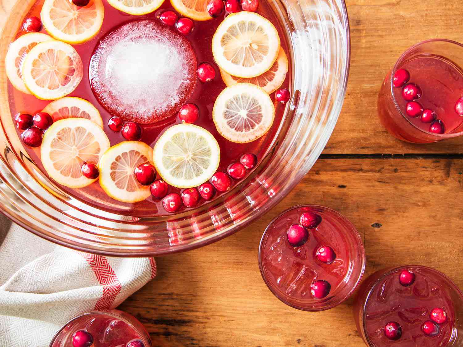 A bowl of Scotch-cranberry cocktail with a few glasses on the side. 