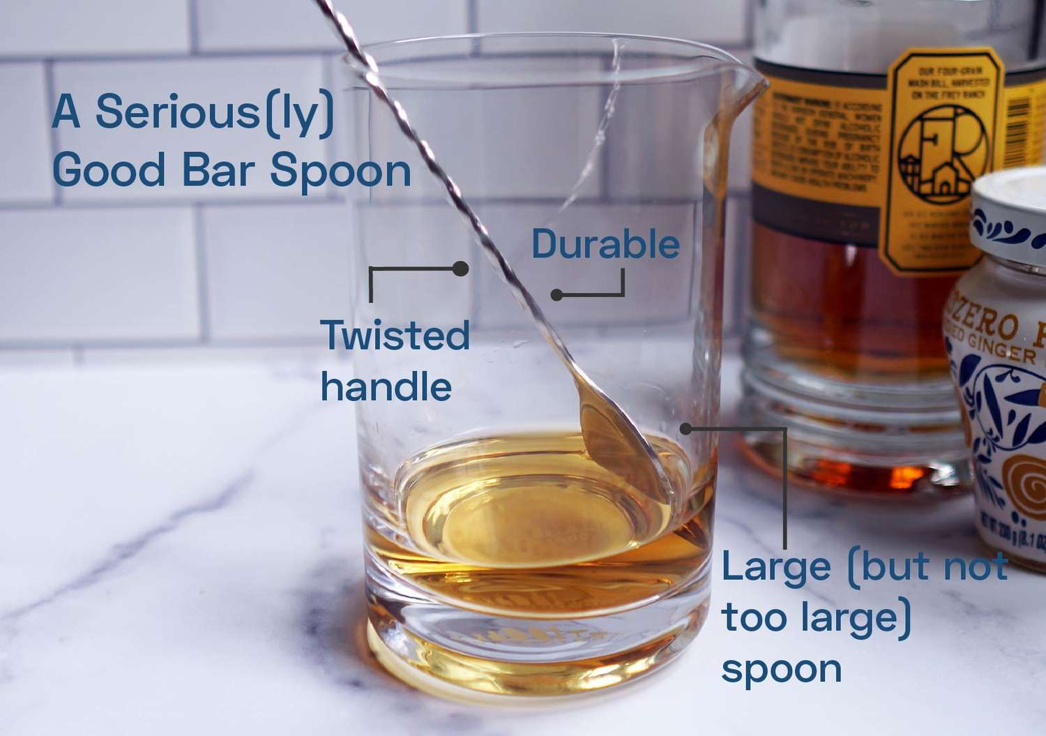 a bar spoon in a mixing glass with liquor at the bottom of it