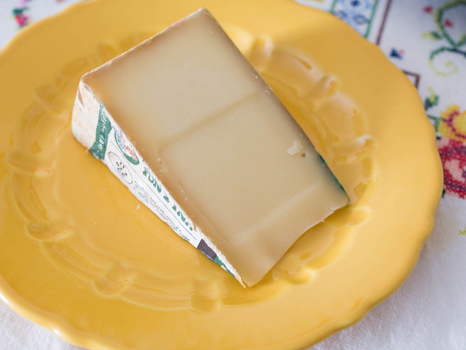 A wedge of fontina val d'aosta cheese on a yellow plate. 