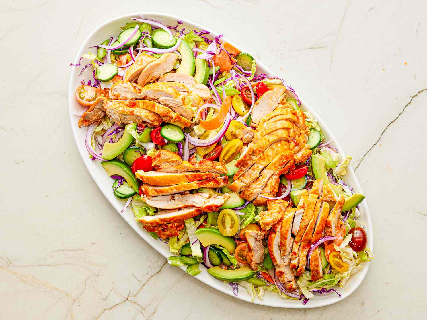 Overhead view of chicken added to salad