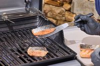 A gloved hand lifting salmon off of the Weber Spirit E-310 Gas Grill with a spatula