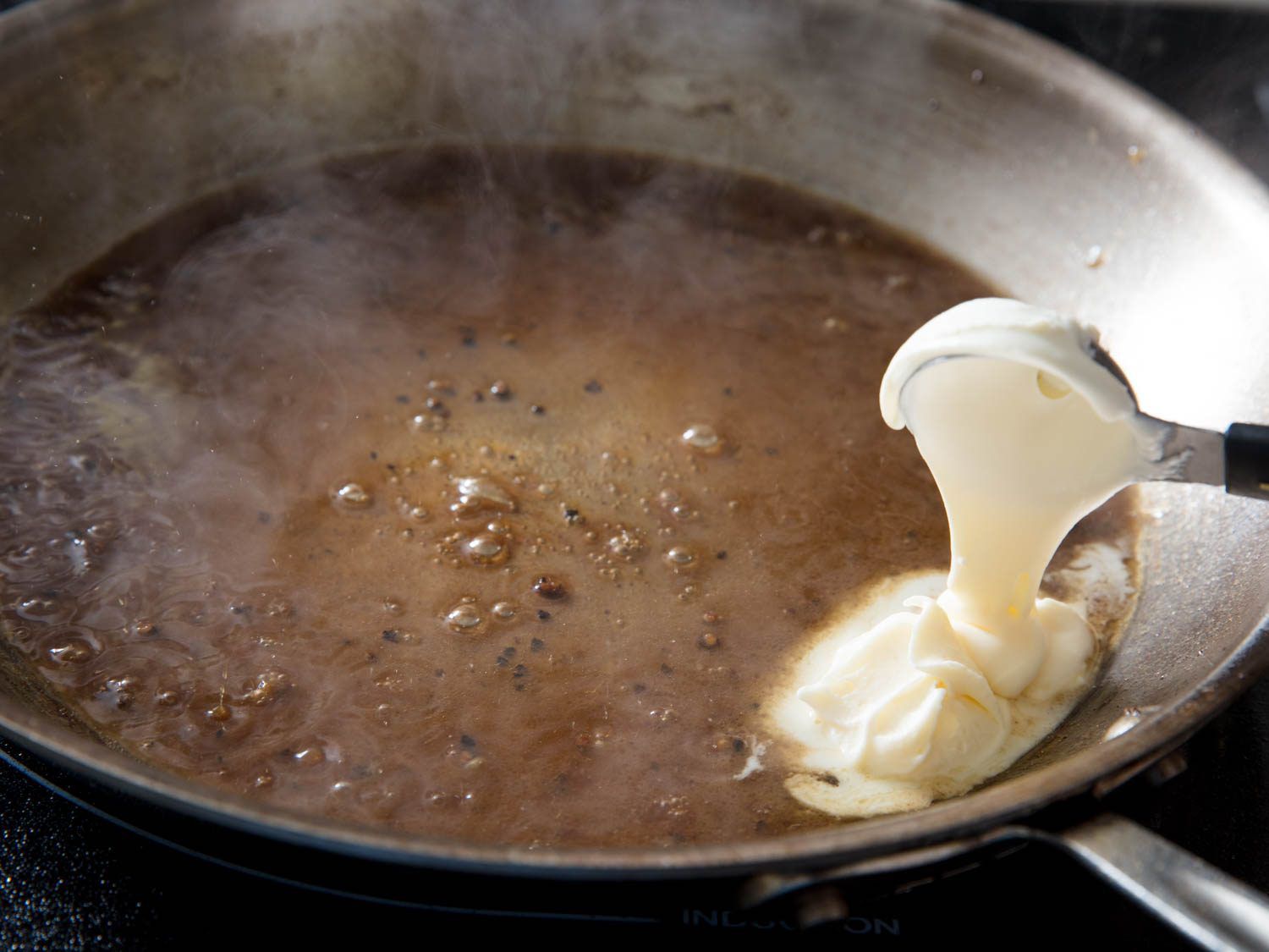 Author adds a spoonful of crème fraîche to the steaming pan sauce.