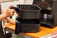 A person removing the inner basket of the Cosori Pro II 5.8 Quart Air Fryer Oven Combo
