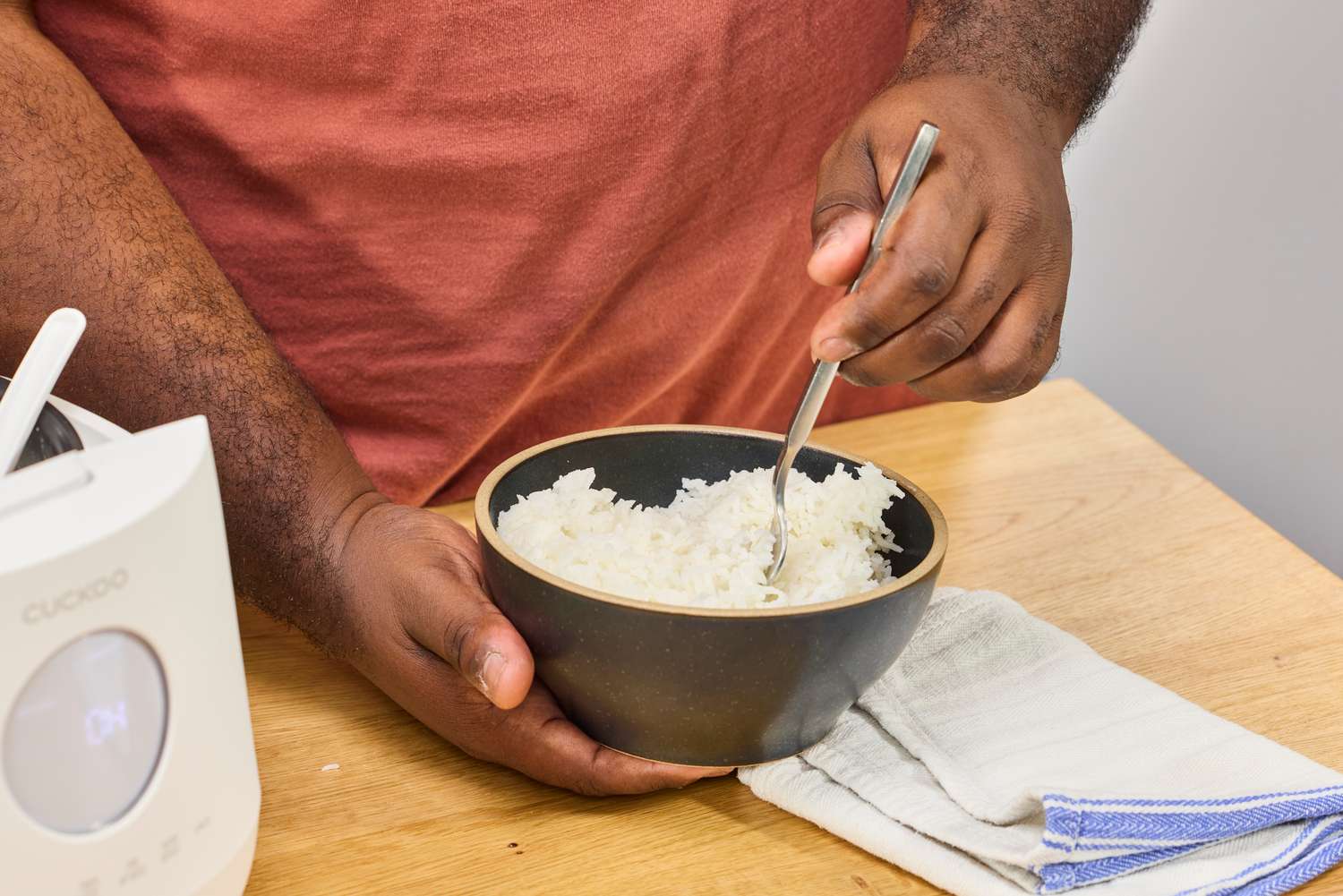 A person eats rice cooked in the Cuckoo 6-Cup Micom Rice Cooker