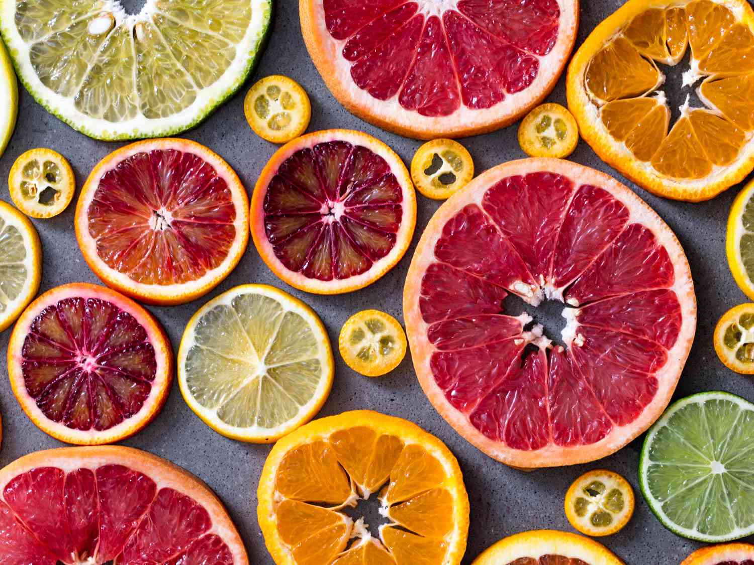 An overhead view of colorful citrus wheels of different sizes an shades of orange, yellow, green, red, and pink.