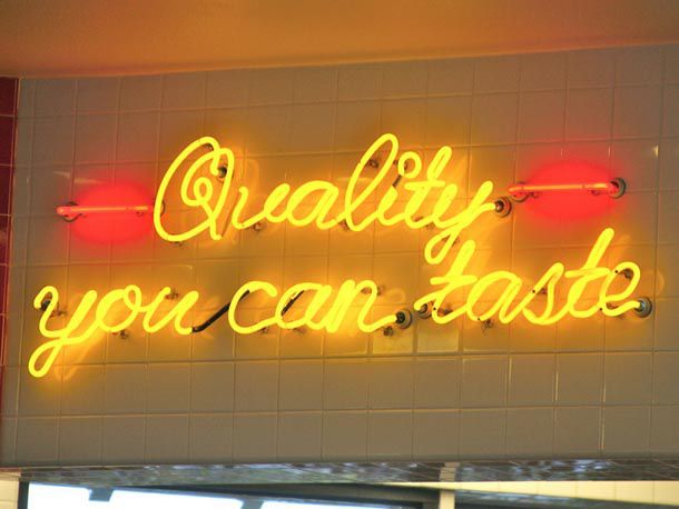 A neon sign at In-N-Out that reads "Quality you can taste"