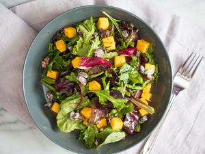 Overhead view of a colorful, mango-studded salad dressed with lemon poppy seed dressing.