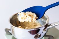 Using a blue silicone serving spoon to scoop oatmeal from a pot