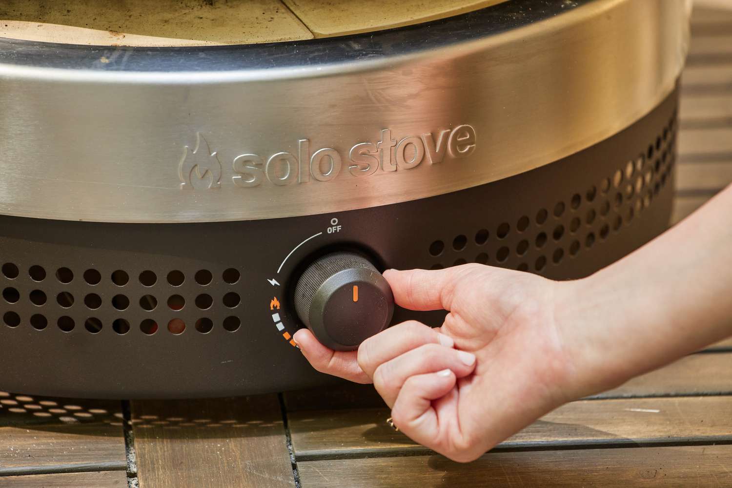A hand turning a nob on the Solo Stove Pi Prime Pizza Oven