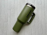 A green Stanley Quencher ProTour tumbler in front of a white brick background
