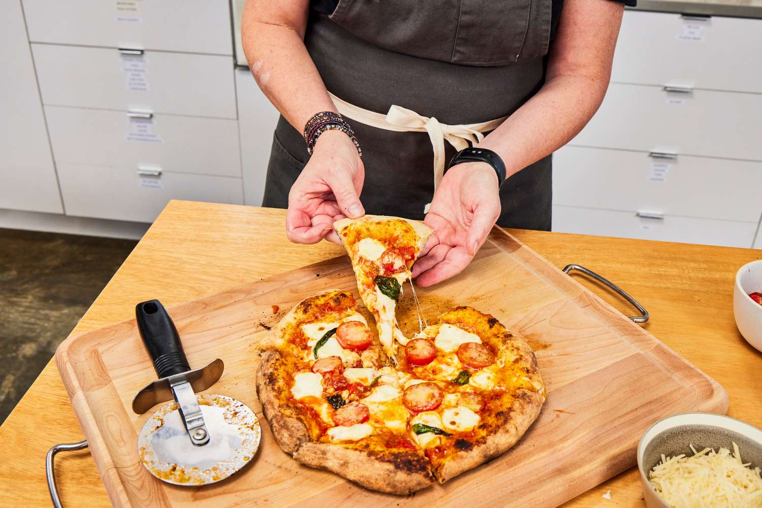 A person removes a slice from a freshly cooked pizza 