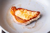 A piece of meat cooking in a pan from the Caraway Cookware Set