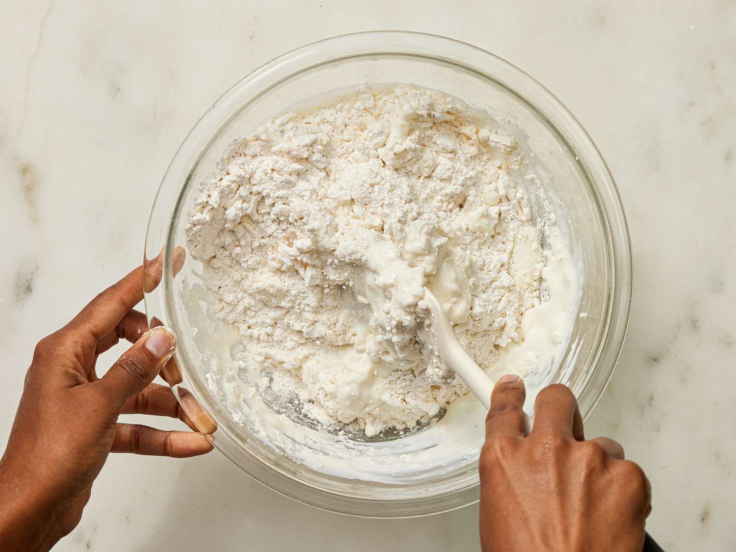 Stirring buttermilk into flour mixture with rubber spatula 