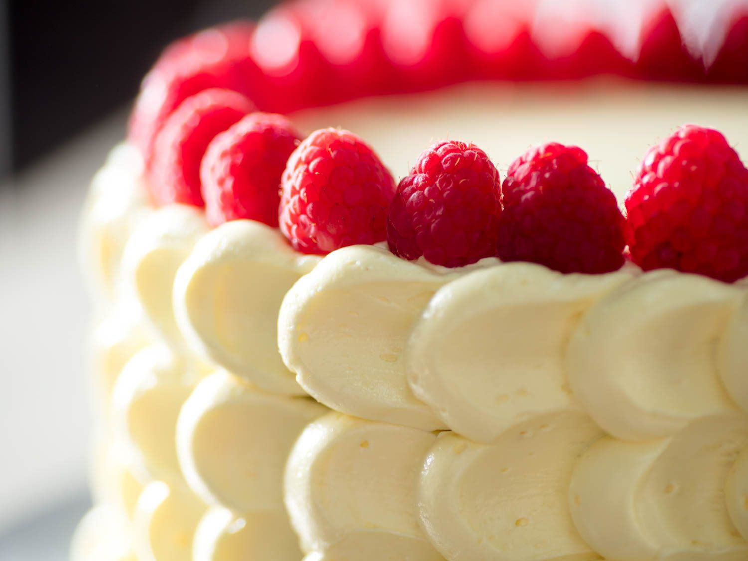 A cake decorated with French buttercream and raspberries.
