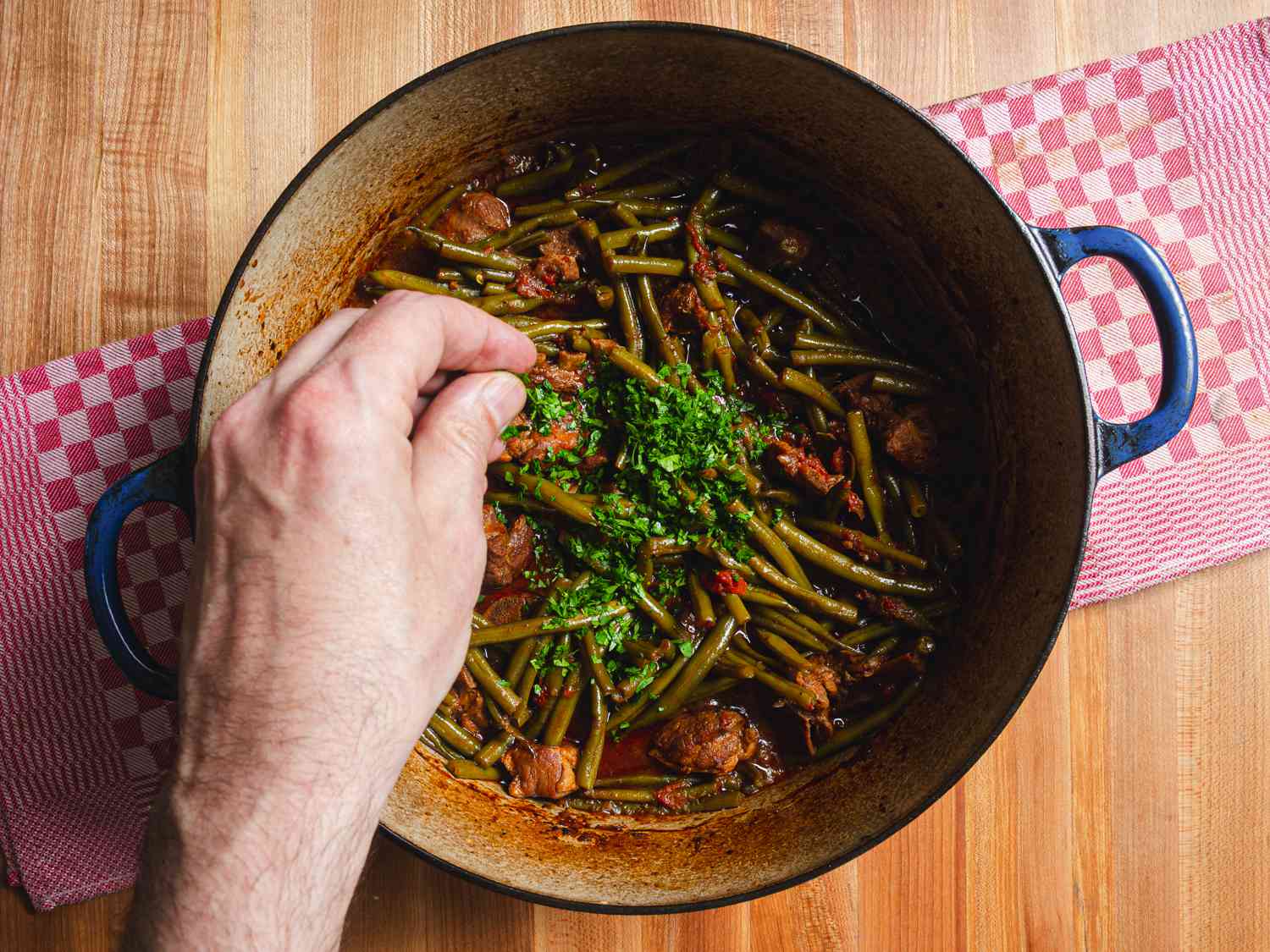 Overhead view of parsley being added into the dutch oven
