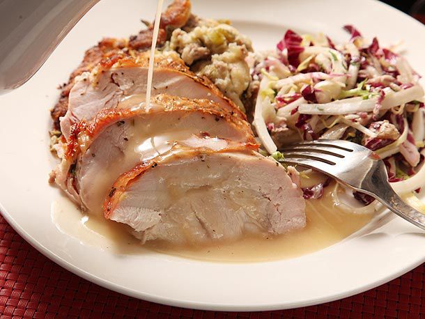 Gravy being drizzled over sliced roast turkey on a plate