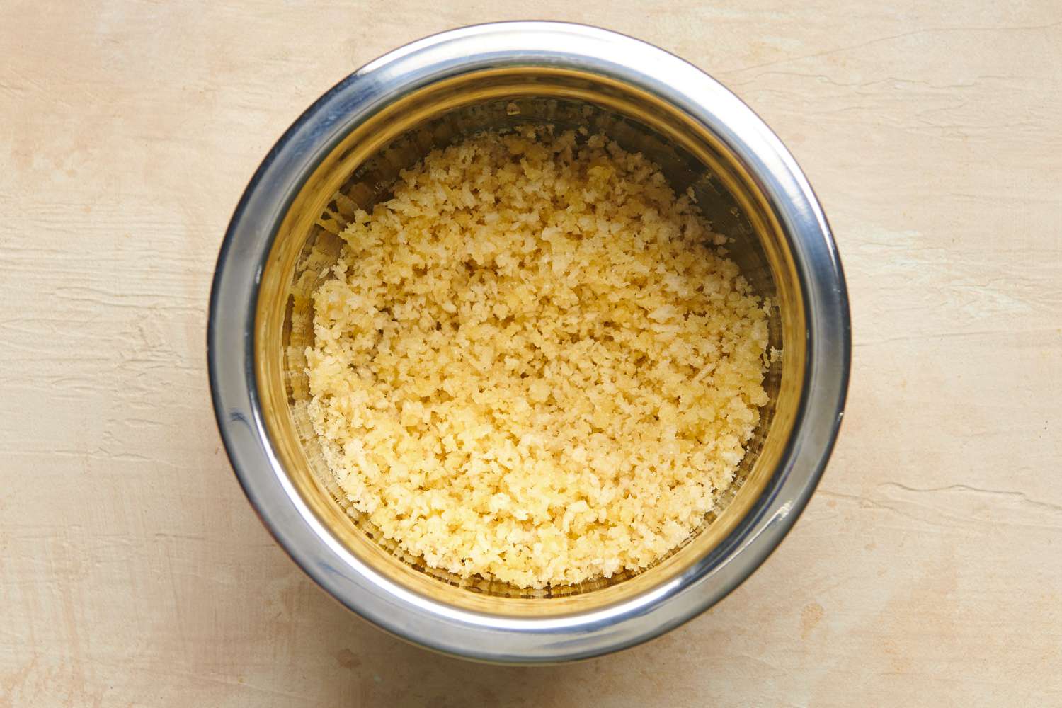 Bread crumbs evenly coated in melted butter and seasoned with salt inside a small bowl.