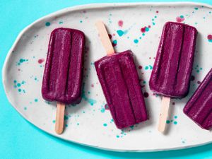 Blueberry yogurt popsicles arranged on a speckled platter