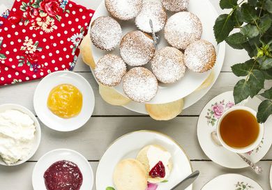 A table full of different British sweets and a cup of tea. 