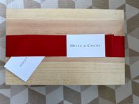 The Olive & Cocoa gift basket with a red ribbon and informational card