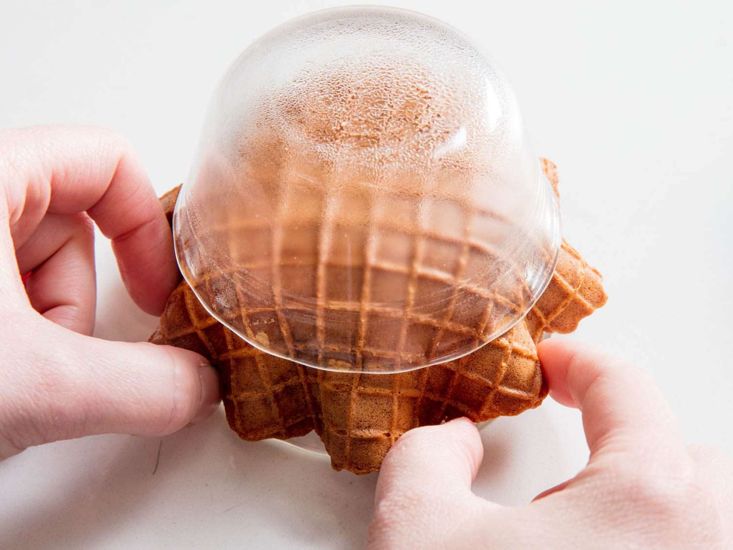 Adding extra frills to a waffle being nestled between two inverted ramekins. 