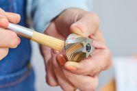 A person cleans a piece from the Comandante C40 Nitro Blade Grinder with a small brush