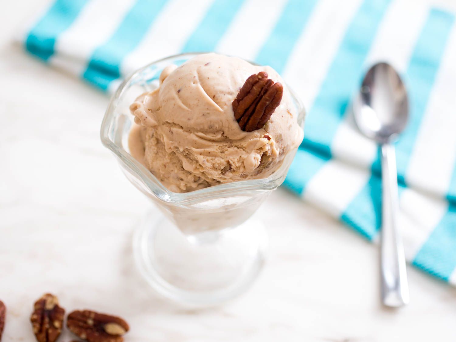 A small parfait glass of browned butter pecan ice cream garnished with a single pecan.