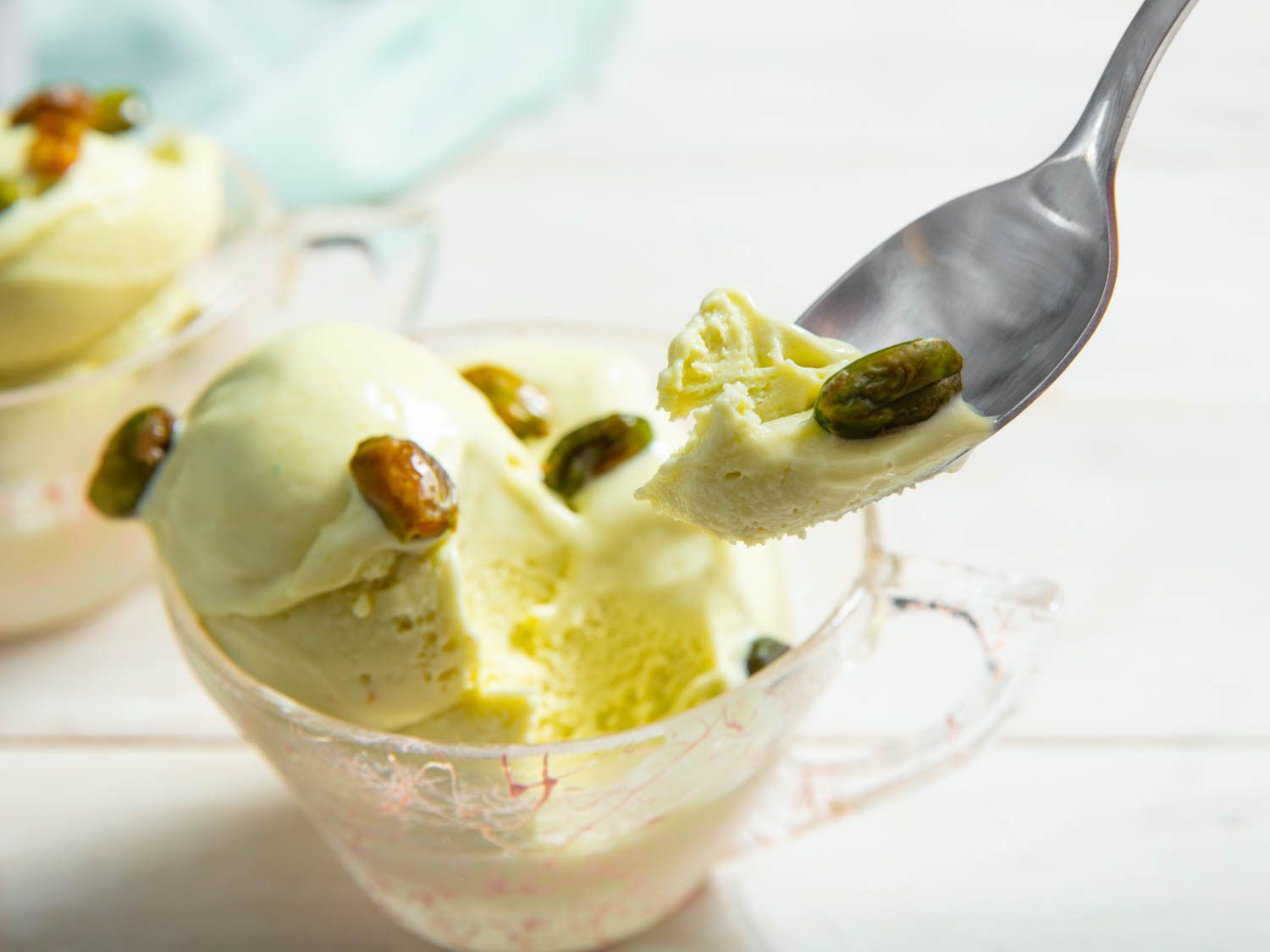 Spooning up a bite of pistachio ice cream from a serving glass.